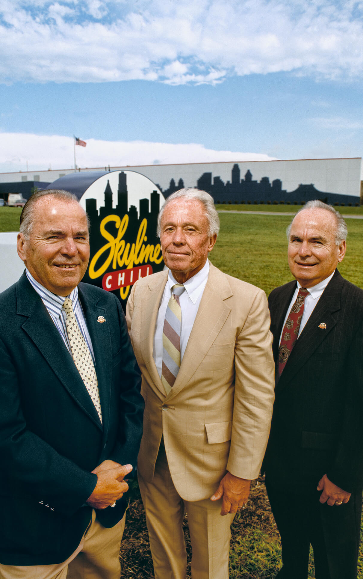 A historical photo of Three older white men standing in suits outside of skyline chili headquarters