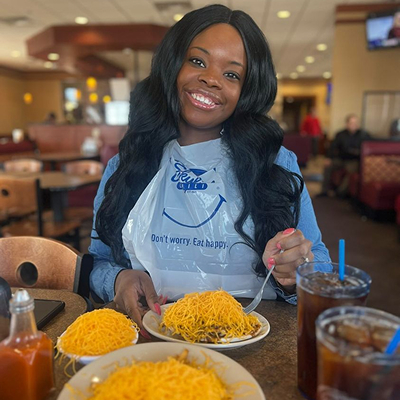 Woman wearing Skyline plastic bib smiling in front of a table full of food